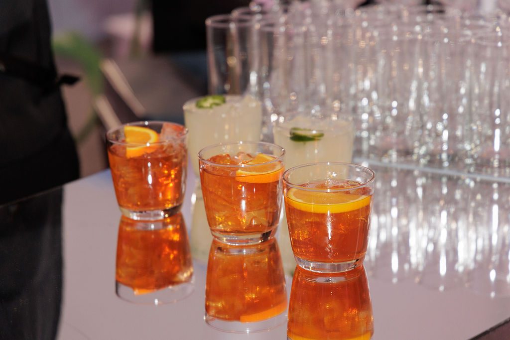 Seasonal cocktails garnished with orange poured at a staffed open bar during an NYC holiday party