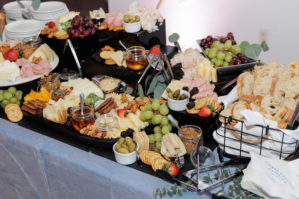 Chef-attended grazing station of charcuterie, cheeses and seasonal fruit on white linen at an employee appreciation event in NYC