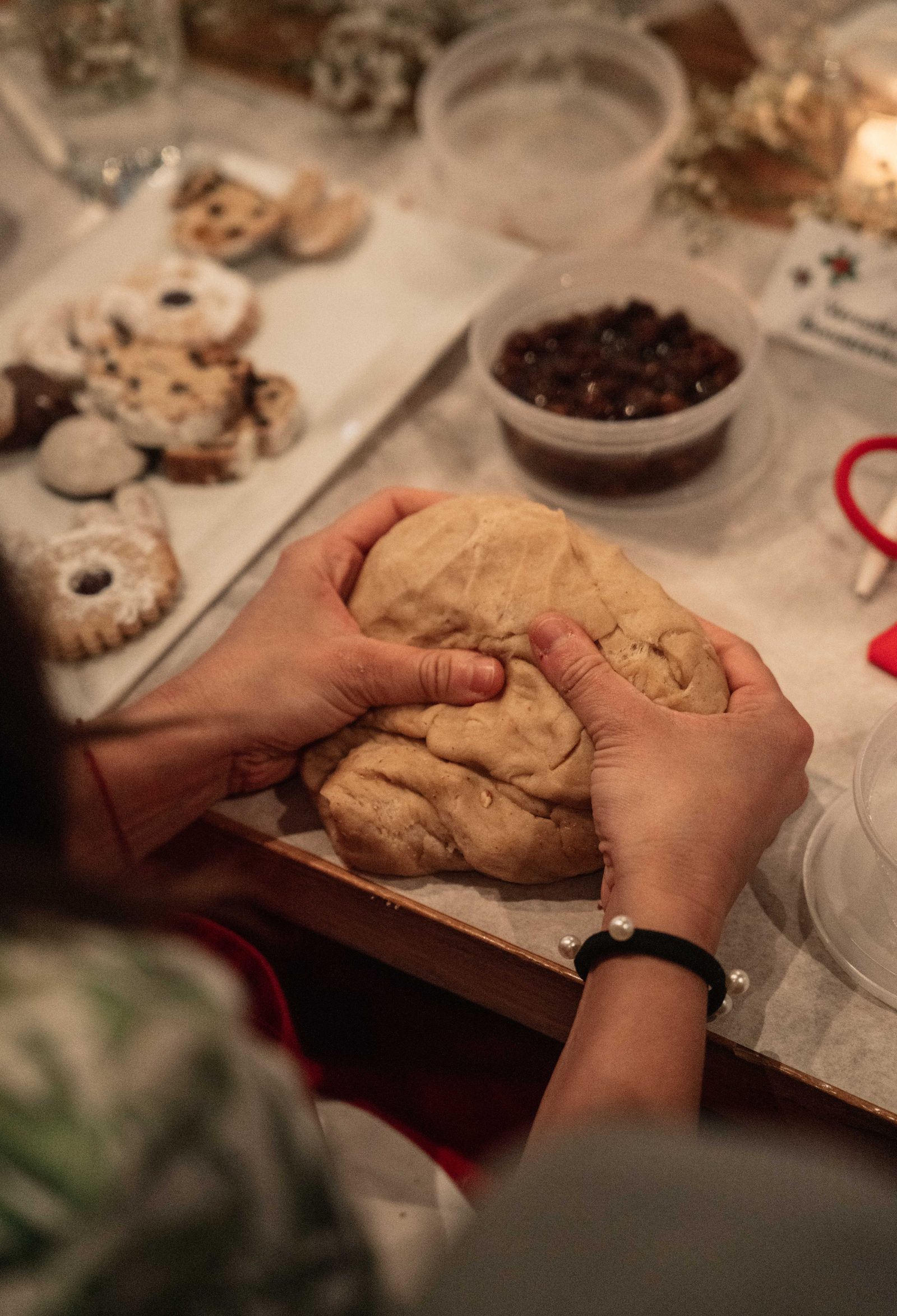 Hands kneading Stollen dough beside freshly baked Austrian Christmas cookies