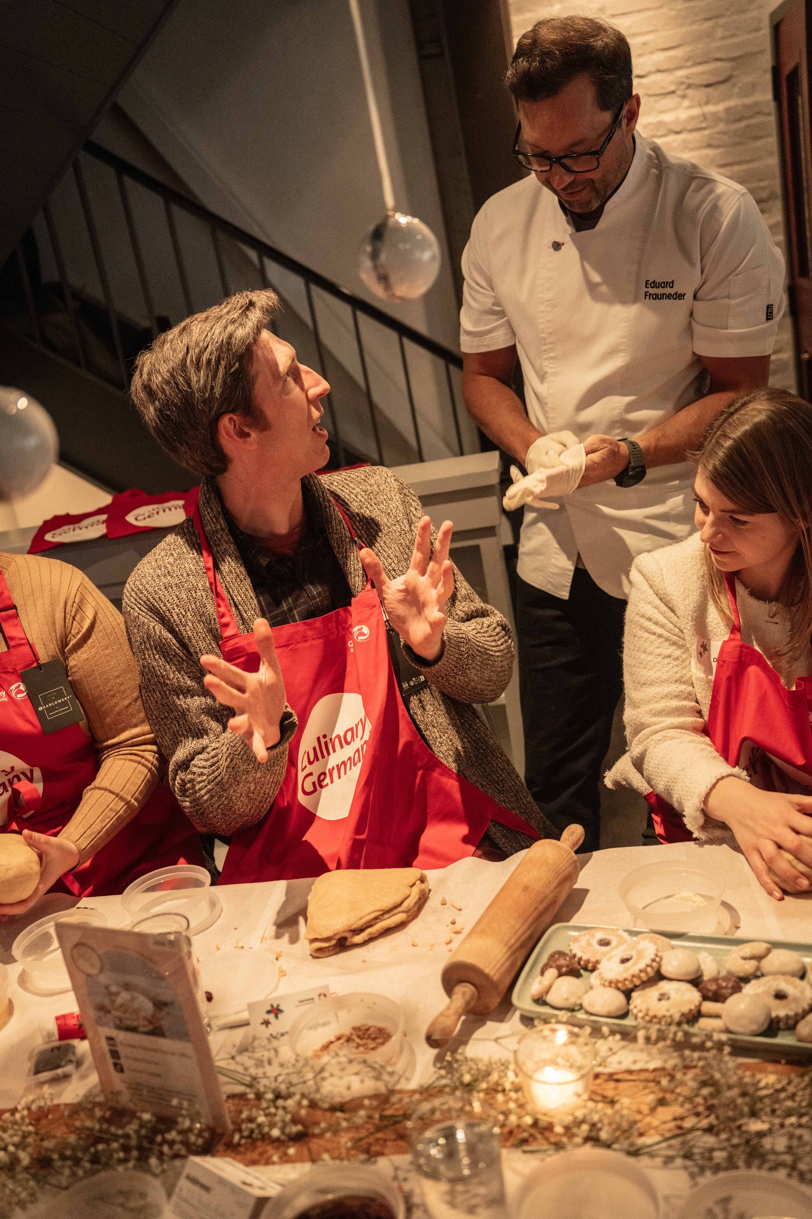 Guests rolling out cookie dough with Chef Eduard Frauneder at a holiday baking workshop